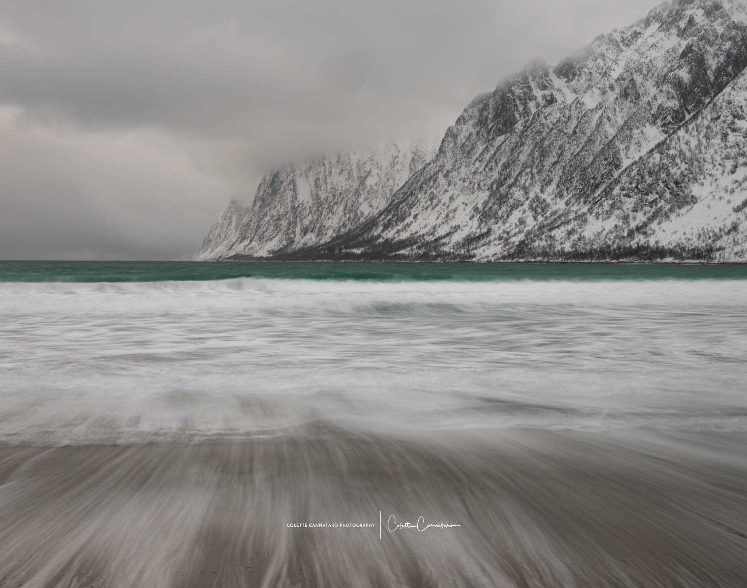 A beautiful Norwegian beach with a pop of turquoise between the mountains and the shore